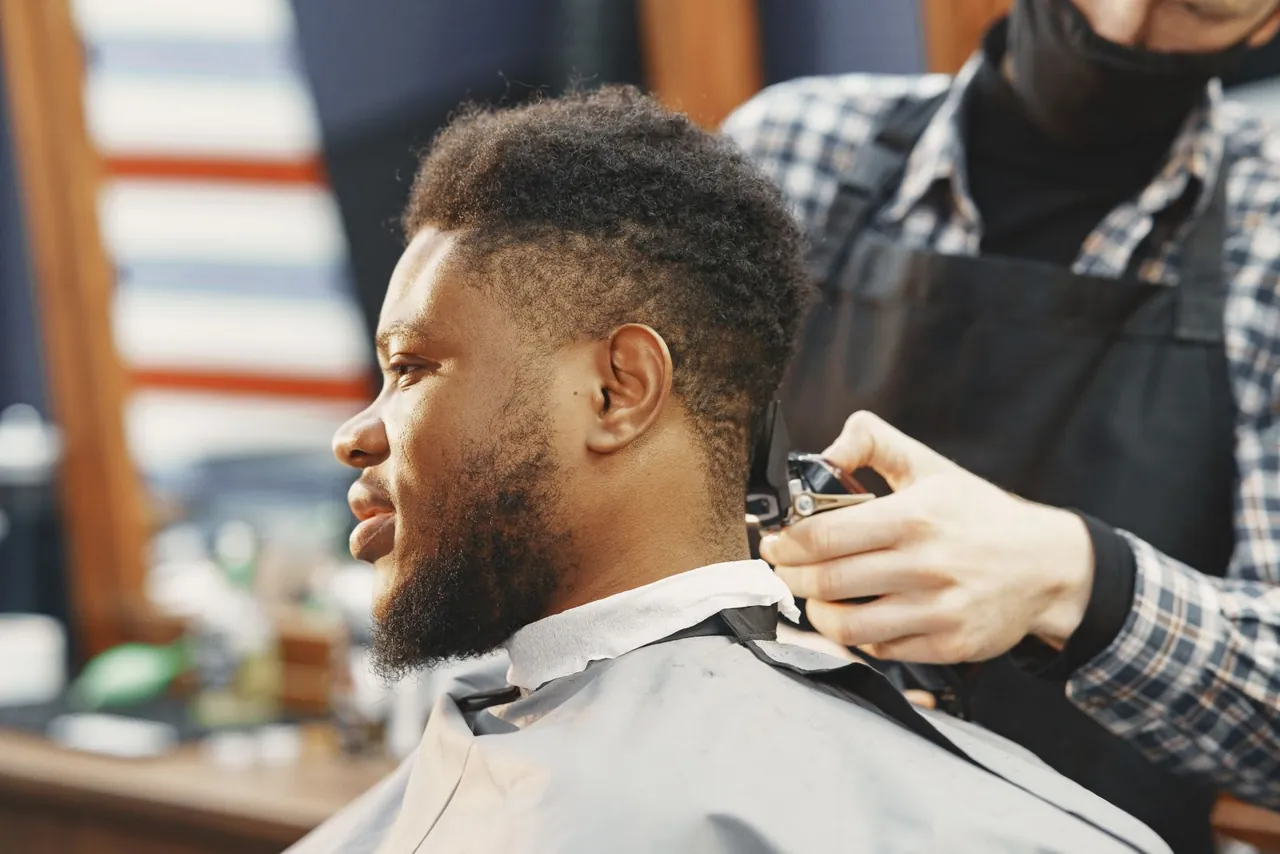 Vista lateral de un corte de cabello con máquina, en una barbería.