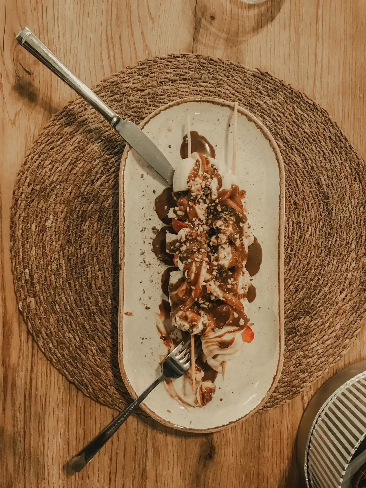 Postre servido con chocolate sobre un plato ovalado.