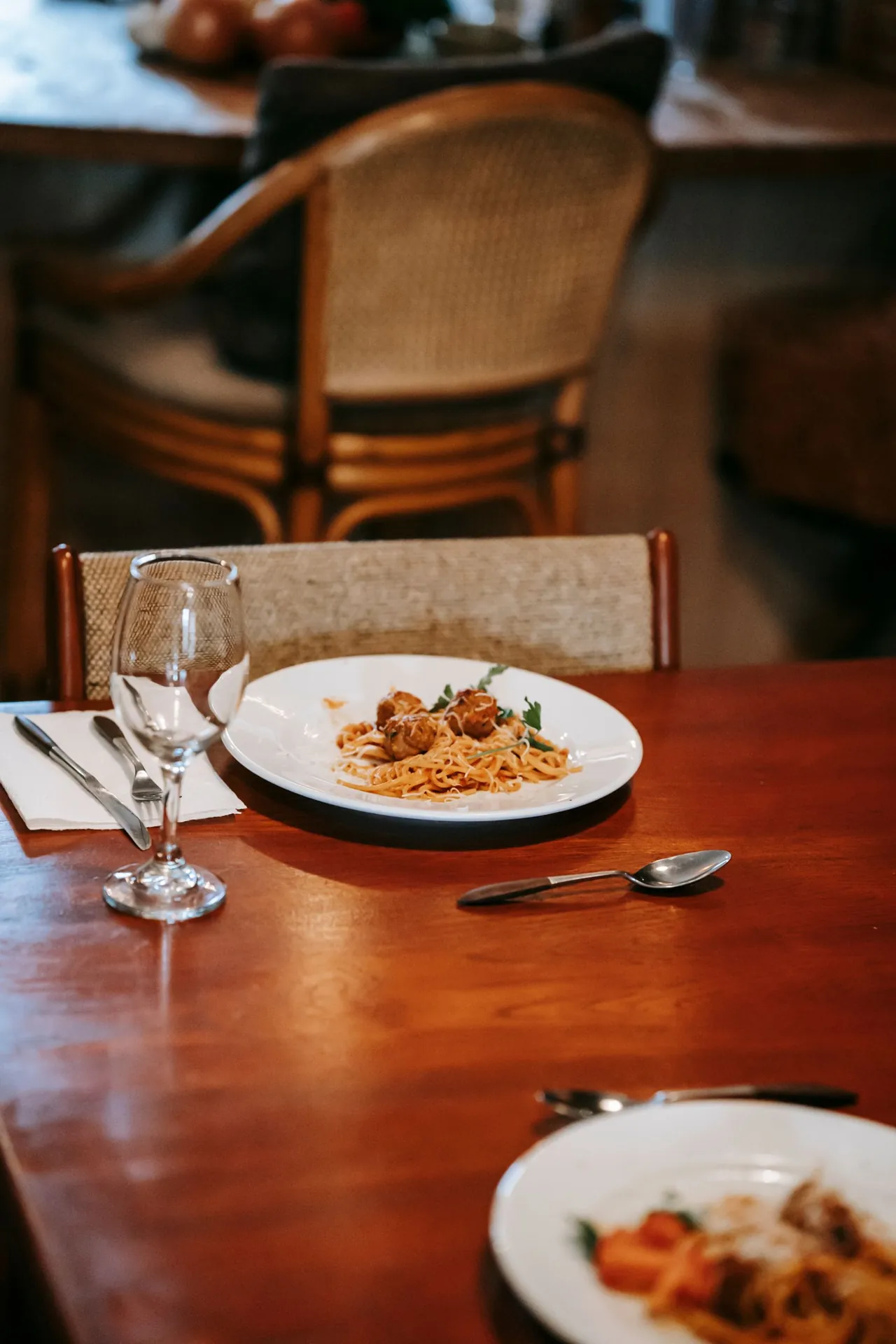 Plato de pasta sobre una mesa de madera con sillas al fondo.