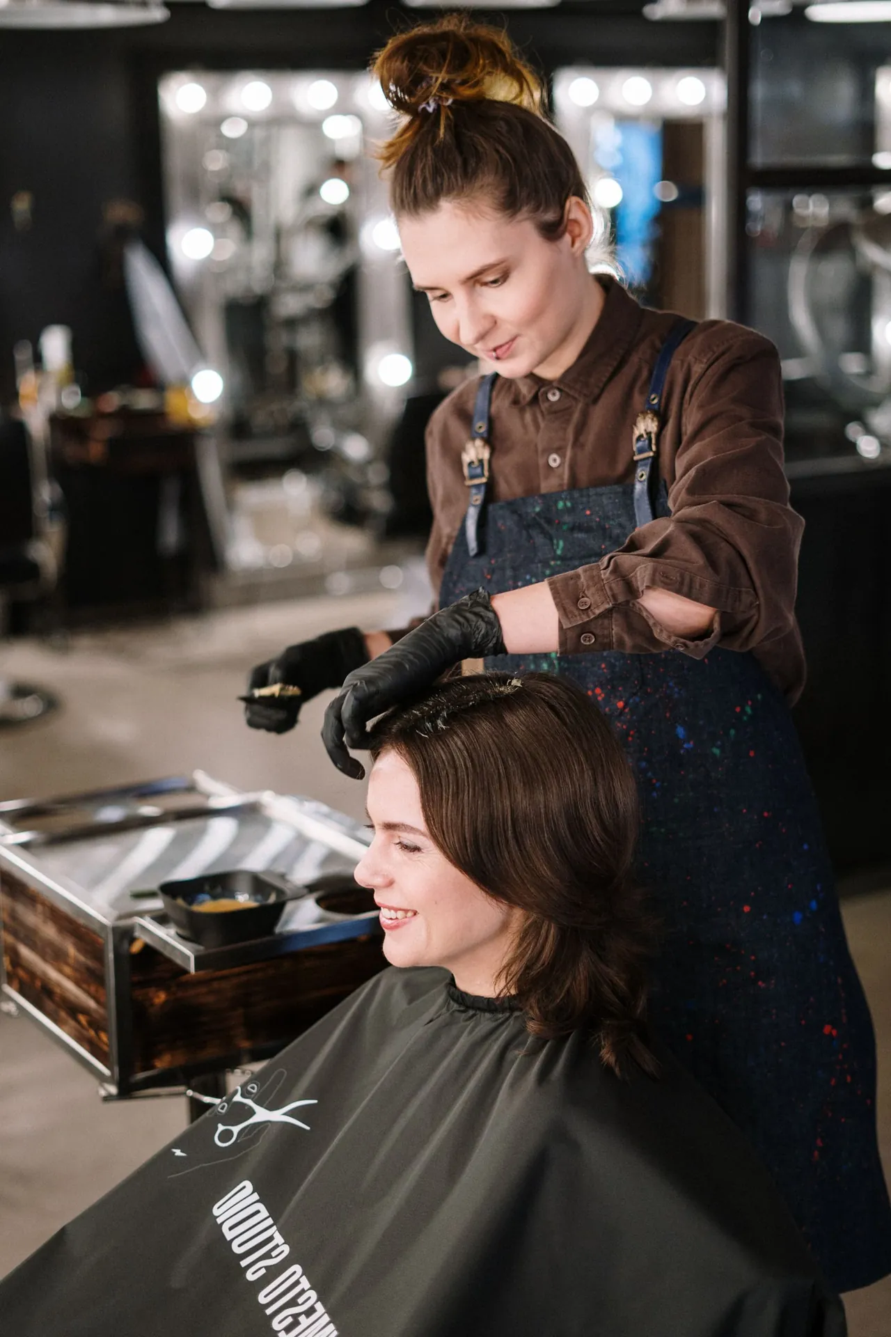 Una profesional aplica color en el cabello de una mujer en un salón; fotografía de stock.