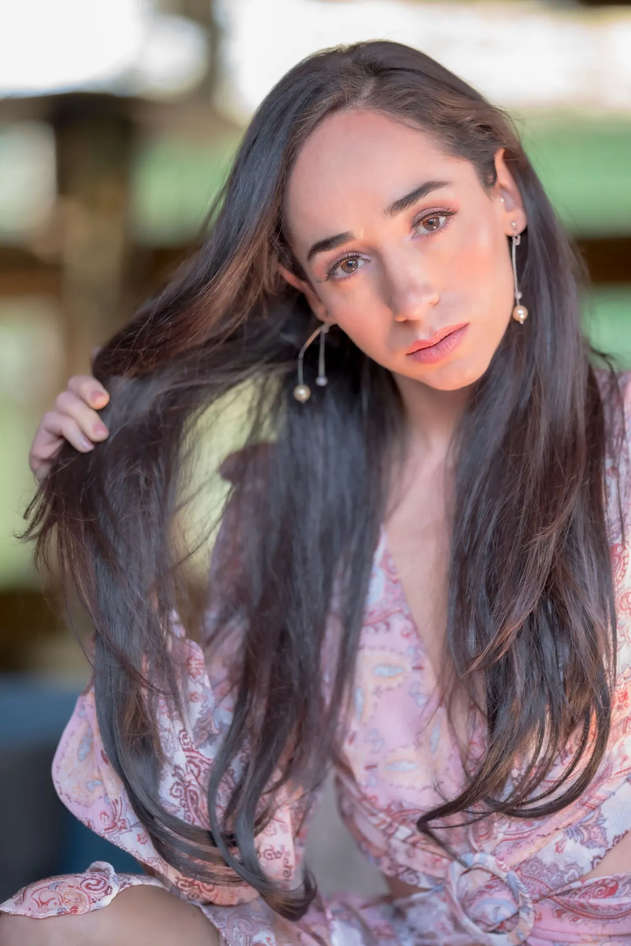 Retrato de una mujer que sostiene un mechón de su cabello largo y oscuro.