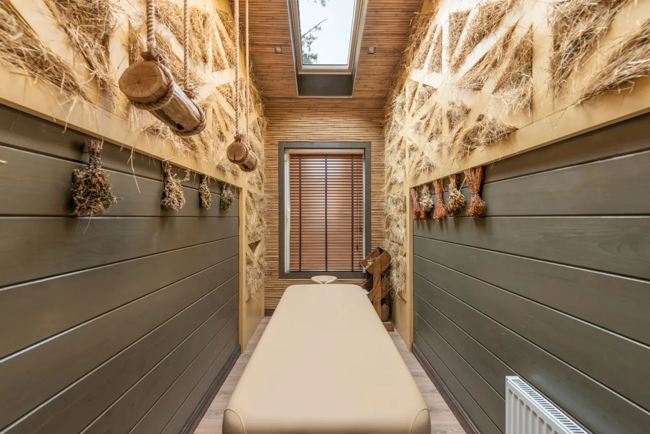 Habitación de spa con camilla, madera cálida y elementos naturales.